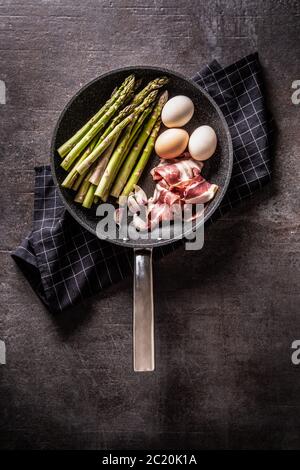 Œufs d'asperge bacon et ail dans une casserole en céramique. Banque D'Images
