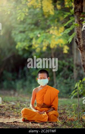 Débutant portant masque méditation sous un arbre dans le temple avec style de vie nouveau normal Banque D'Images