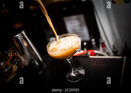 Un cocktail alcoolisé orange est versé dans un verre Banque D'Images