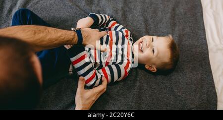 Un père caucasien jouant avec son fils sur le canapé allongé et souriant jusqu'à la caméra Banque D'Images