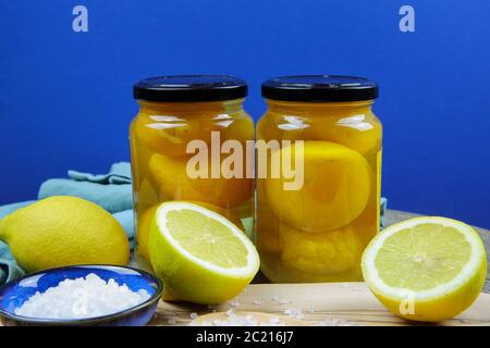 Préparation de citrons salés marinés conservés au maroc : gros plan de tranches isolées d'agrumes jaunes, bol bleu et cuillère en bois avec sa mer épaisse Banque D'Images