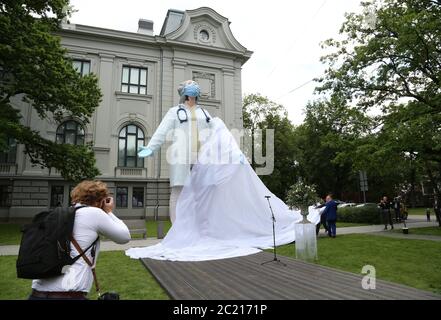 Riga, Lettonie. 15 janvier 2012. Une femme photographie la statue « les acteurs du monde » du sculpteur A. Bikse devant le Musée national d'art de Lettonie, en signe de gratitude et d'appréciation pour les efforts désintéressés des médecins et des infirmières pendant la pandémie de Corona. Elle montre un médecin portant un protège-bouche et des gants, qui a quitté la salle de traitement et s'étire avec ses yeux fermés pour se préparer à sa prochaine tâche. Credit: Alexander Welscher/dpa/Alay Live News Banque D'Images