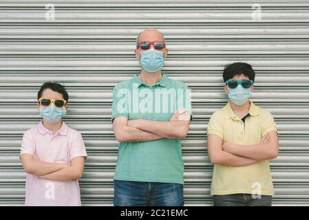 père avec ses fils portant un masque médical et des lunettes de soleil à l'extérieur Banque D'Images