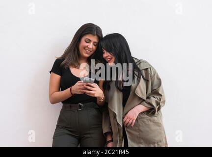 Deux jeunes femmes utilisent un smartphone sur un blanc arrière-plan Banque D'Images