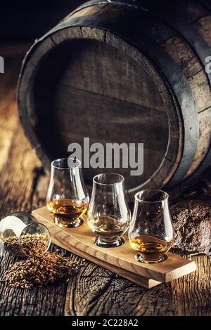 Des coupes de whisky de dégustation Glencairn avec baril de bois, tourbe et orge à côté Banque D'Images