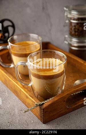 Boisson glacée au café Dalgona sur fond de plateau en bois. Café instantané ou espresso en poudre fouetté avec du sucre et de l'eau chaude. Café avec lait Banque D'Images