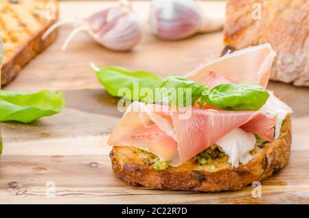 Crostini avec jambon forêt noire, fromage Parmesan et pesto au basilic Banque D'Images