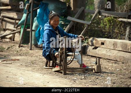 Une femme Lanten, âgée, indigène et ethnique, filant dans son village de la province de Luang Namtha, dans le nord du Laos. Banque D'Images