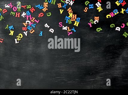 Les petites lettres en bois multicolores de l'alphabet anglais sur un tableau noir, l'espace de copie, le retour à l'école Banque D'Images