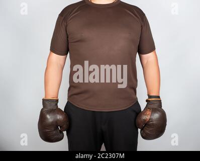 Jeune homme se tient en tenue très old vintage brown des gants de boxe sur ses mains, fond blanc Banque D'Images