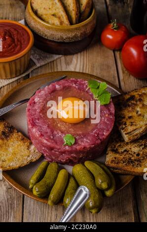 Tartare de boeuf, un plat délicieux plat de protéines avec des épices, de la moutarde, l'oeuf et le pain frit à l'ail Banque D'Images