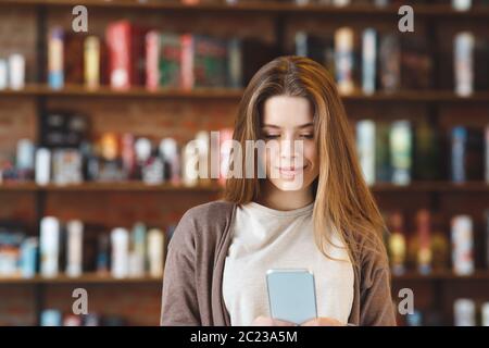 Une fille souriante regarde ses photos sur son téléphone portable tout en se relaxant Banque D'Images