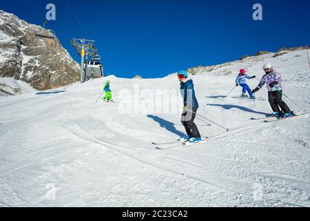 Groupe d'enfants ski en descente sur une pente alpine en formation scolaire ensemble l'un après l'autre Banque D'Images