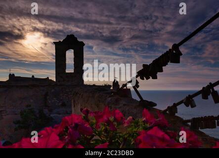 Clocher en pierre au-dessus de la mer dans le soleil couchant, Peschici, péninsule du Gargano, Italie Banque D'Images