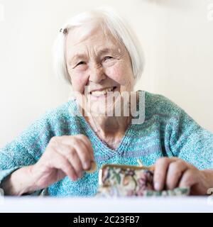 Personnes âgées gaies 96 ans woman sitting at table à la maison heureux avec elle dans son portefeuille d'épargne-retraite après le paiement des factures. L'épargne-retraite un Banque D'Images