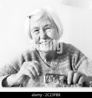 Personnes âgées gaies 96 ans woman sitting at table à la maison heureux avec elle dans son portefeuille d'épargne-retraite après le paiement des factures. L'épargne-retraite un Banque D'Images