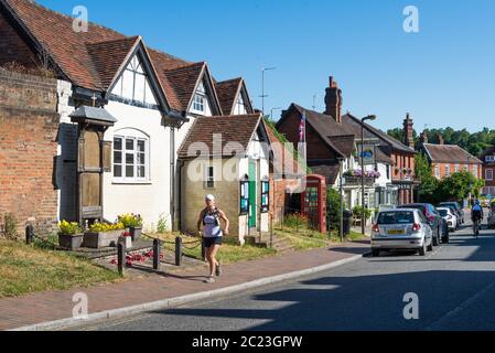 Une femme jogger passe devant la salle de lecture de l'église St. Giles à High Street, Chalfont St. Giles, Buckinghamshire, Angleterre, Royaume-Uni Banque D'Images