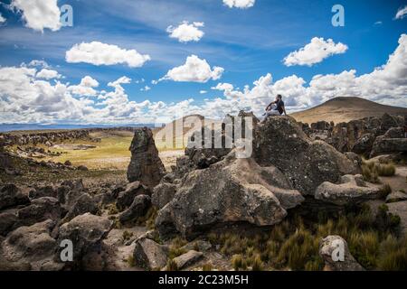 jeune homme debout sur un grand rocher au milieu de la forêt, nuages et ciel bleu Banque D'Images