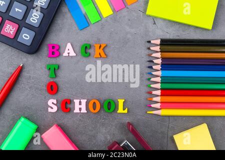 L'acheminement de fournitures scolaires sur un fond gris foncé. La vue du sommet. Retour à l'école. Mise à plat Banque D'Images