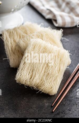 Nouilles de riz blanc non cuites et baguettes sur table noire. Banque D'Images