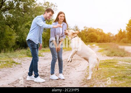 Un jeune couple donne un cadeau à son chien heureux Banque D'Images