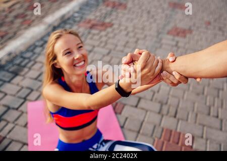 Homme aide une belle femme sportive de se lever après avoir fait un sport l'exercice sur tapis. Mode de vie sain. Banque D'Images