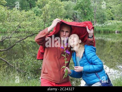 homme et femme se cachant de la pluie sur le lac Banque D'Images