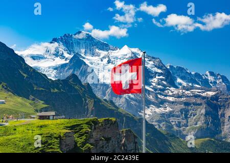 Drapeau suisse et touristes admirent les sommets des montagnes Monch et Jungfrau sur un point de vue de Mannlichen, Oberland bernois Suisse Banque D'Images