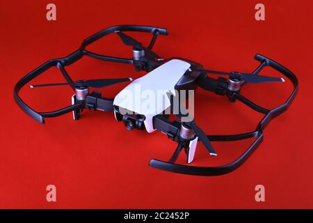 UAV Drone copter isolé sur fond blanc, gros plan. Petit quadricoptère de drone avec protection par hélice sur fond rouge. Vol de drone en toute sécurité. ONU Banque D'Images