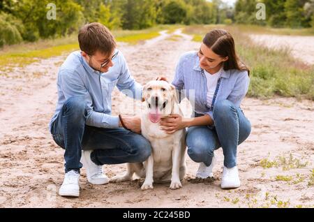 Portrait d'un jeune couple heureux qui embrasse son chien charmant Banque D'Images