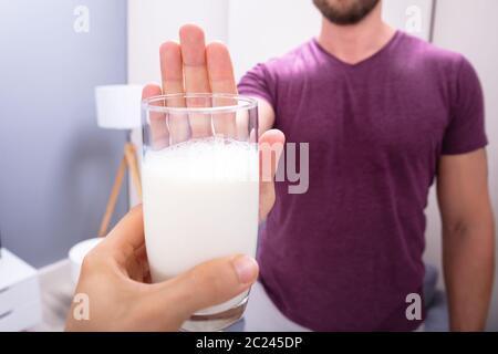 Portrait d'un homme rejetant Verre de lait offert par personne à la maison Banque D'Images