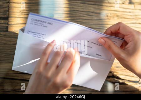 Close-up de l'homme d'affaires d'ouverture de l'enveloppe avec un chèque en bois de plus de 24 Banque D'Images