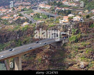 vue aérienne sur le paysage du pont autoroutier de funchal, qui pénètre dans un tunnel dans la vallée avec des bâtiments et des rues du cit Banque D'Images