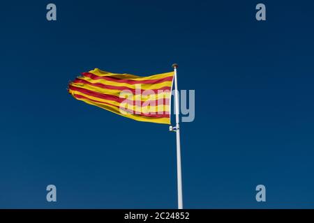 Low angle view au drapeau catalan avec bords déchirés en agitant plus de ciel clair. Banque D'Images