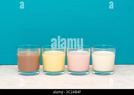 Chocolat, Banane et fraise milkshakes et lait frais en gobelets en verre contre un arrière-plan bleu sarcelle Banque D'Images