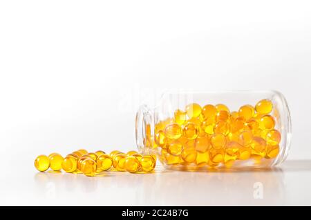 Comprimé jaune crumble capsules à partir d'une bouteille en verre sur un fond blanc Banque D'Images