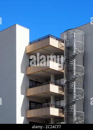 les appartements modernes sont dotés d'un balcon avec cheminée en spirale et de murs blancs aux rayons du soleil et au ciel bleu Banque D'Images