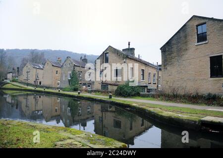 rues de maisons mitoyennes le long du canal rochdale dans le pont hebden avec des bâtiments reflétés dans l'eau en hiver Banque D'Images