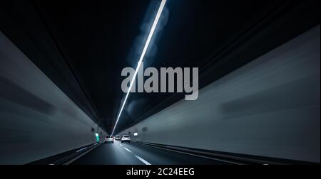 Les voitures sur une route allant à travers un long tunnel moderne (motion image floue ; couleur tonique libre) Banque D'Images