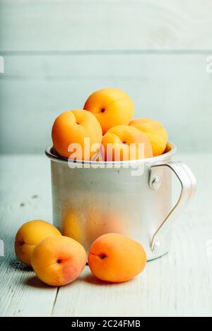 Abricots moelleux en metal mug sur la surface en bois clair Banque D'Images