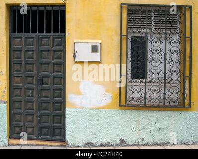 porte en bois et fenêtre barrée dans une ancienne maison espagnole traditionnelle avec des murs peints en jaune dégommage Banque D'Images