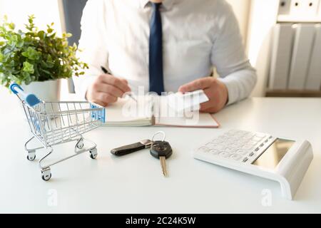 Le calcul des frais d'affaires commercial pour achat de voiture, tenant en main les reçus. Vide panier et clés de voiture à l'avant Banque D'Images