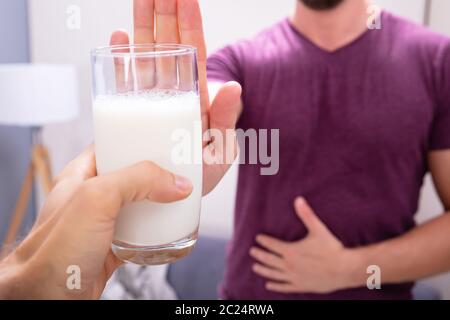 Portrait d'un homme rejetant Verre de lait offert par personne à la maison Banque D'Images