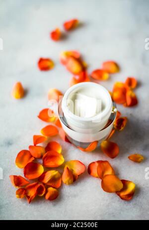 Crème hydratante pour le visage et pétales de fleurs sur marbre, produit cosmétique de luxe Banque D'Images