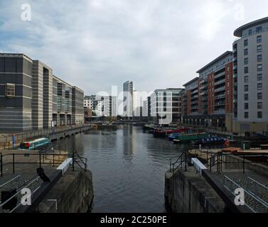 une vue sur le quai de leeds depuis les portes d'écluse montrant des bâtiments de développement au bord de l'eau et des immeubles d'appartements avec des bateaux à moteur amarrés moi Banque D'Images