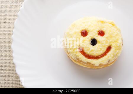 Un donut smiley sur une assiette blanche Banque D'Images