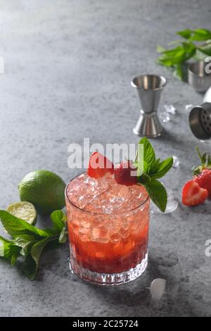 Cocktail d'alcool frais avec gin, fraises, soda, glaçon et lime. Boisson savoureuse. Banque D'Images