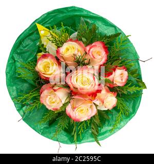 Roses bicolores jaunes et rouges disposées avec des branches et des verts frais avec papier de soie vert, isolé sur blanc. Banque D'Images