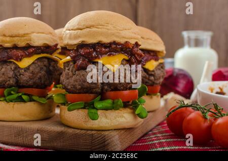 Curseurs de boeuf avec sauce barbecue maison, cheddar, tomates cerises et microgreens Banque D'Images