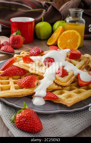 Gaufres maison avec sirop d'érable et fraises, crème fraîche surmontée, boissons fraîches à l'orange Banque D'Images